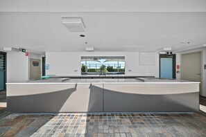 Un espace intérieur moderne et spacieux, doté d’un comptoir central, d’une grande fenêtre et d’un sol carrelé.