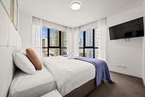 A hotel room with a bed, a TV, and large windows with a city view. - Surfers Paradise Escape| carpark|Resort Facilities (Surfers Paradise)