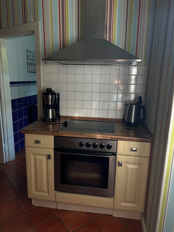 Een praktische keuken met een inbouwoven, een kookplaat en een koffiezetapparaat.