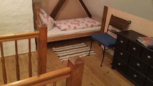 Quarto com cama beliche, uma escrivaninha pequena e um armário.