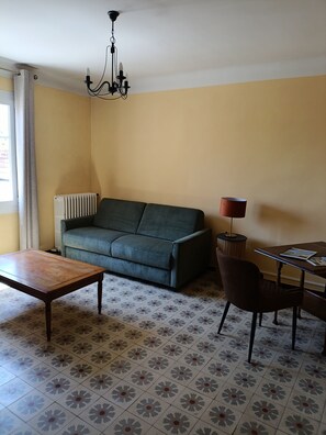 A living room with a sofa, a coffee table, a lamp, a chair, and a radiator. - A typical Provençal house, just a 10-minute walk from Almanarre Beach! (Hyères)