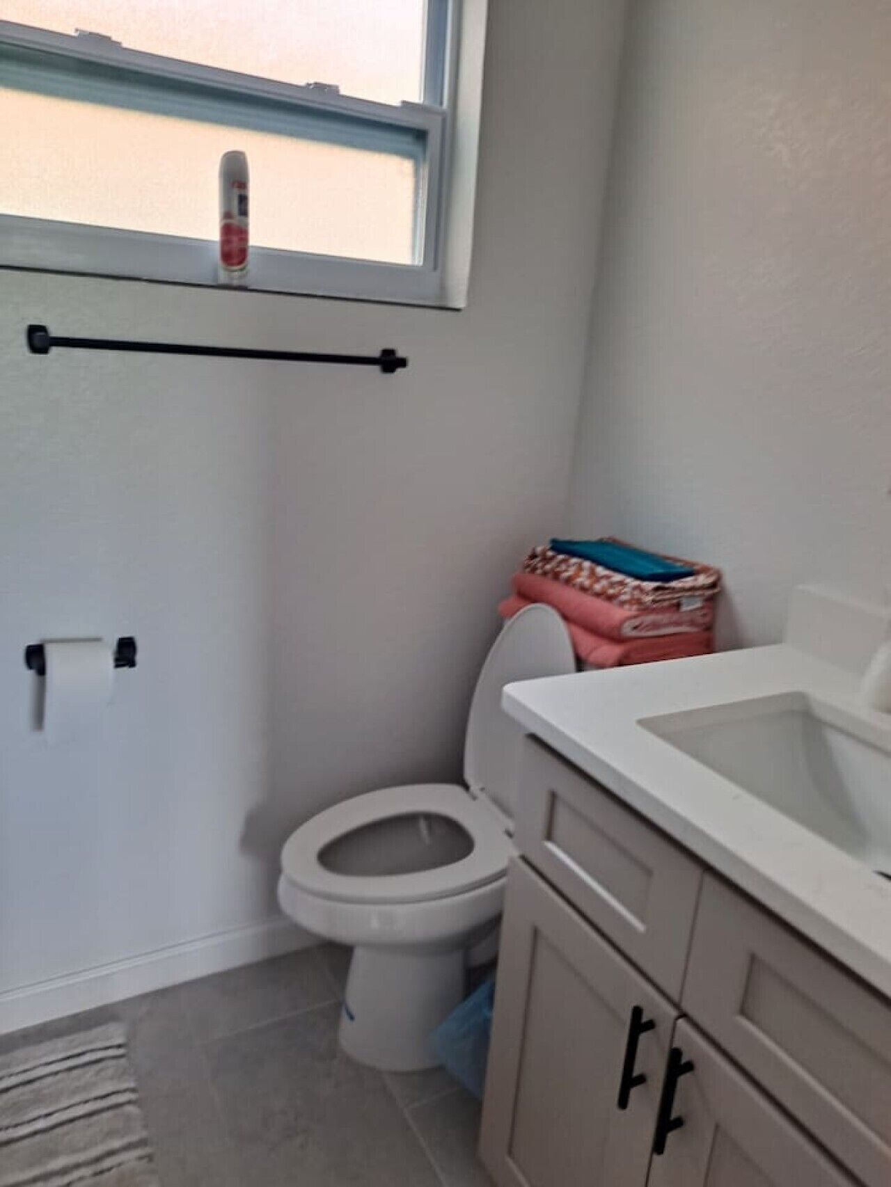 A bathroom with a toilet, a sink, and a window.