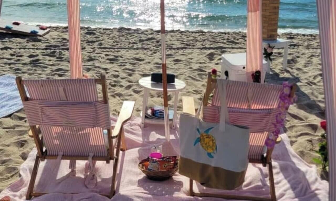 Un espace aménagé près de la plage, avec deux chaises à rayures, une table et un bol décoratif.