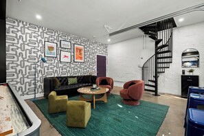 A modern living room with a patterned wall, a black staircase, and a green rug. - The Stables 2 - Minigolf, Firepits, Games, BBQ (Louisville)