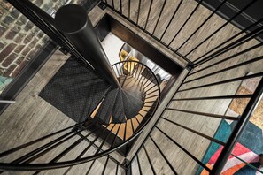 A spiral staircase with a black metal railing and a textured floor. - The Stables 2 - Minigolf, Firepits, Games, BBQ (Louisville)