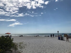 En strand med et telt, parasoller og mennesker.