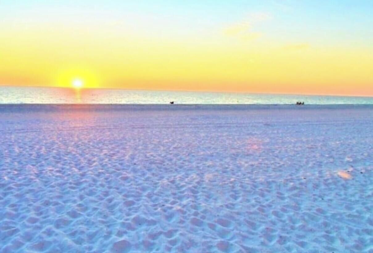 Una playa con un atardecer de fondo.