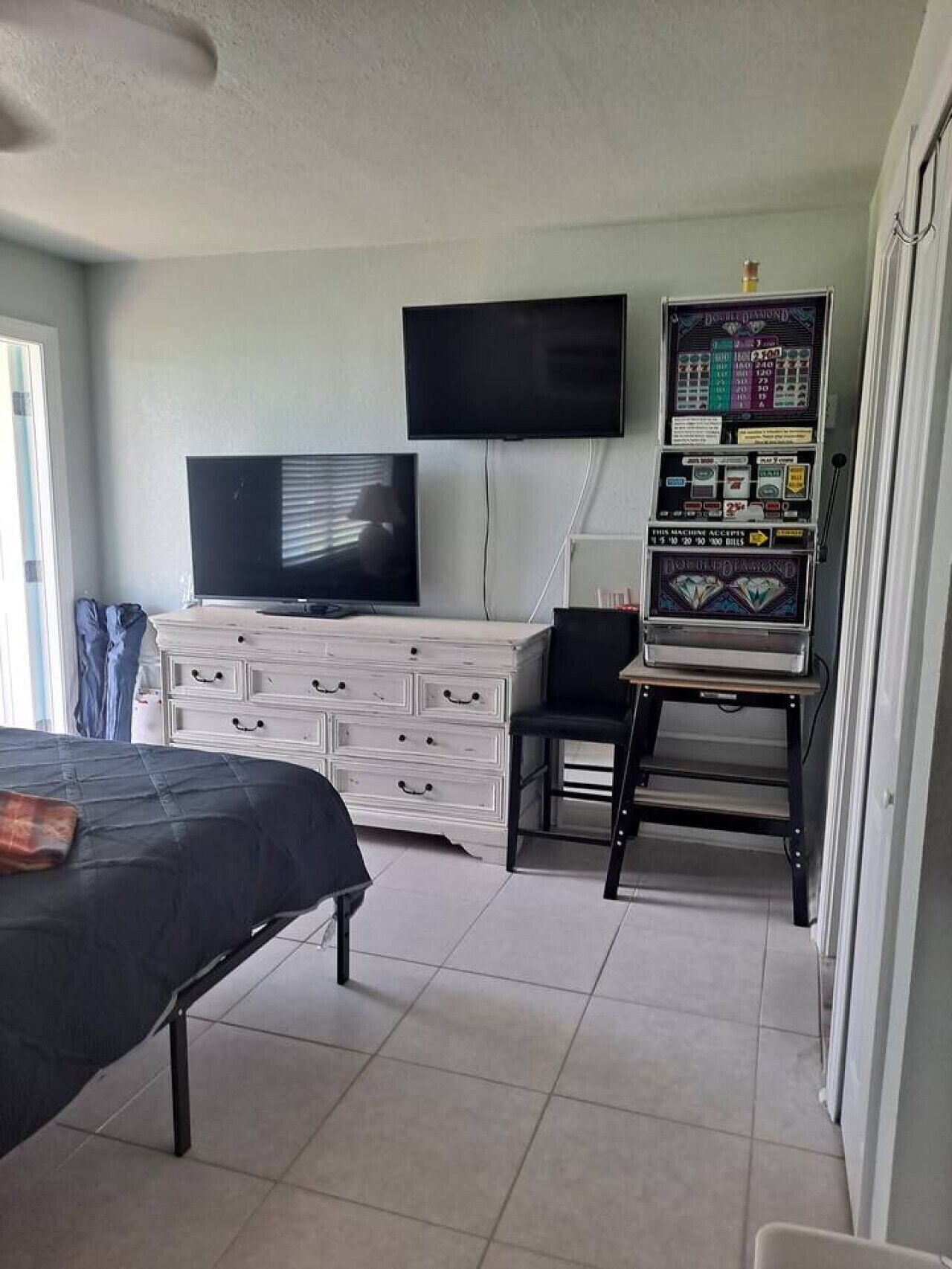 A bedroom with a bed, a dresser, a television, and a slot machine.
