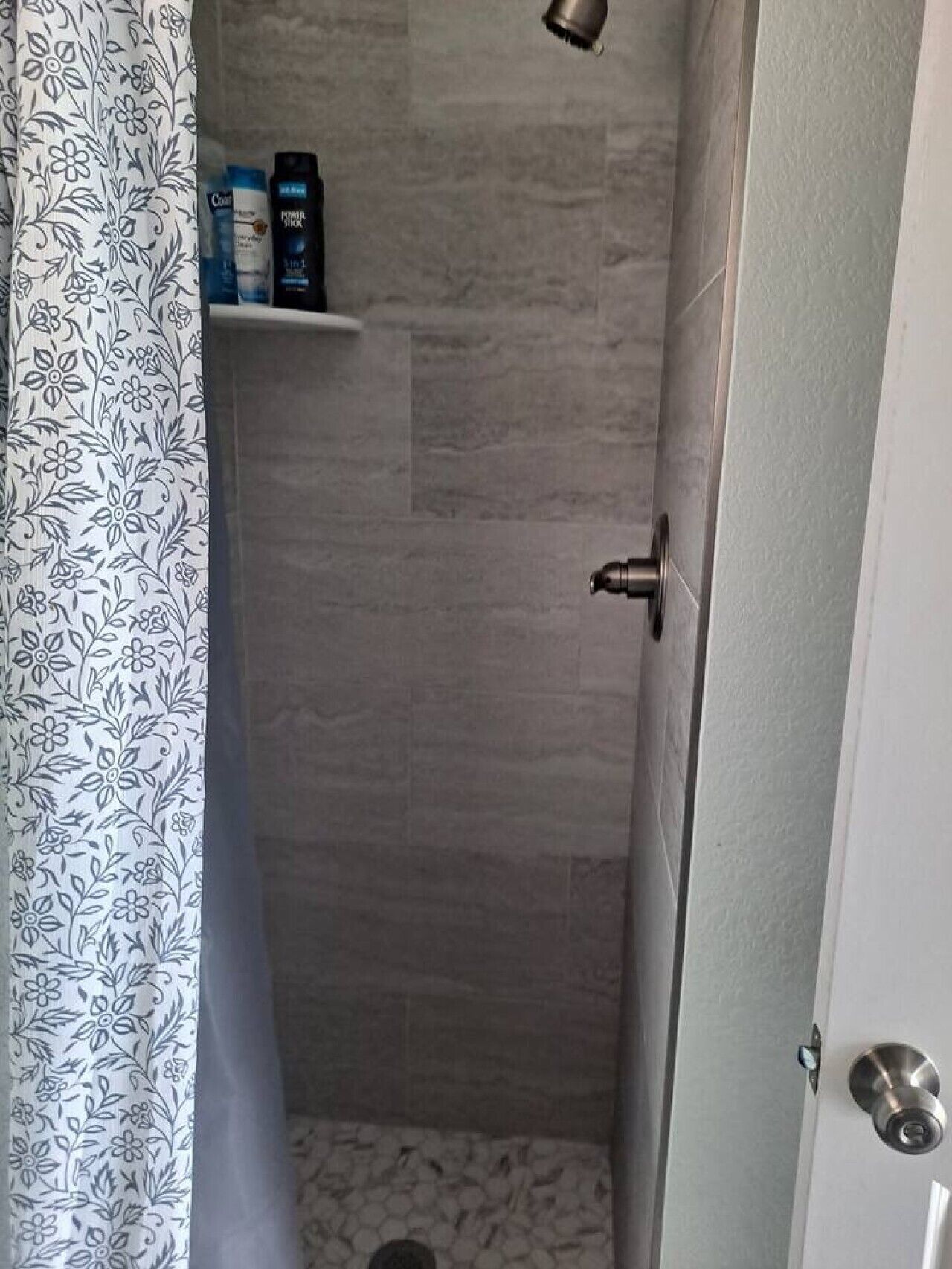 Une salle de bain équipée d’une douche, de toilettes et d’une étagère où sont rangés les articles de toilette.