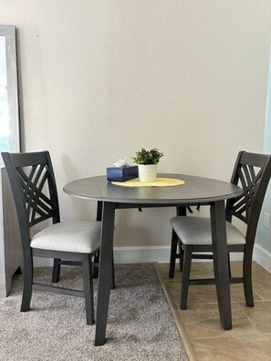 A round dining table with two chairs, a tissue box, and a small plant on the table.