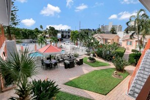 A hotel courtyard with outdoor seating, a swimming pool, and a view of the surrounding neighborhood.