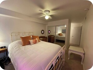 Ein Schlafzimmer mit einem Bett, einem Nachttisch, einem Deckenventilator und einem Kleiderschrank.