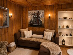 Une pièce chaleureuse avec un canapé marron, un tableau encadré et une étagère ornée d’objets décoratifs.