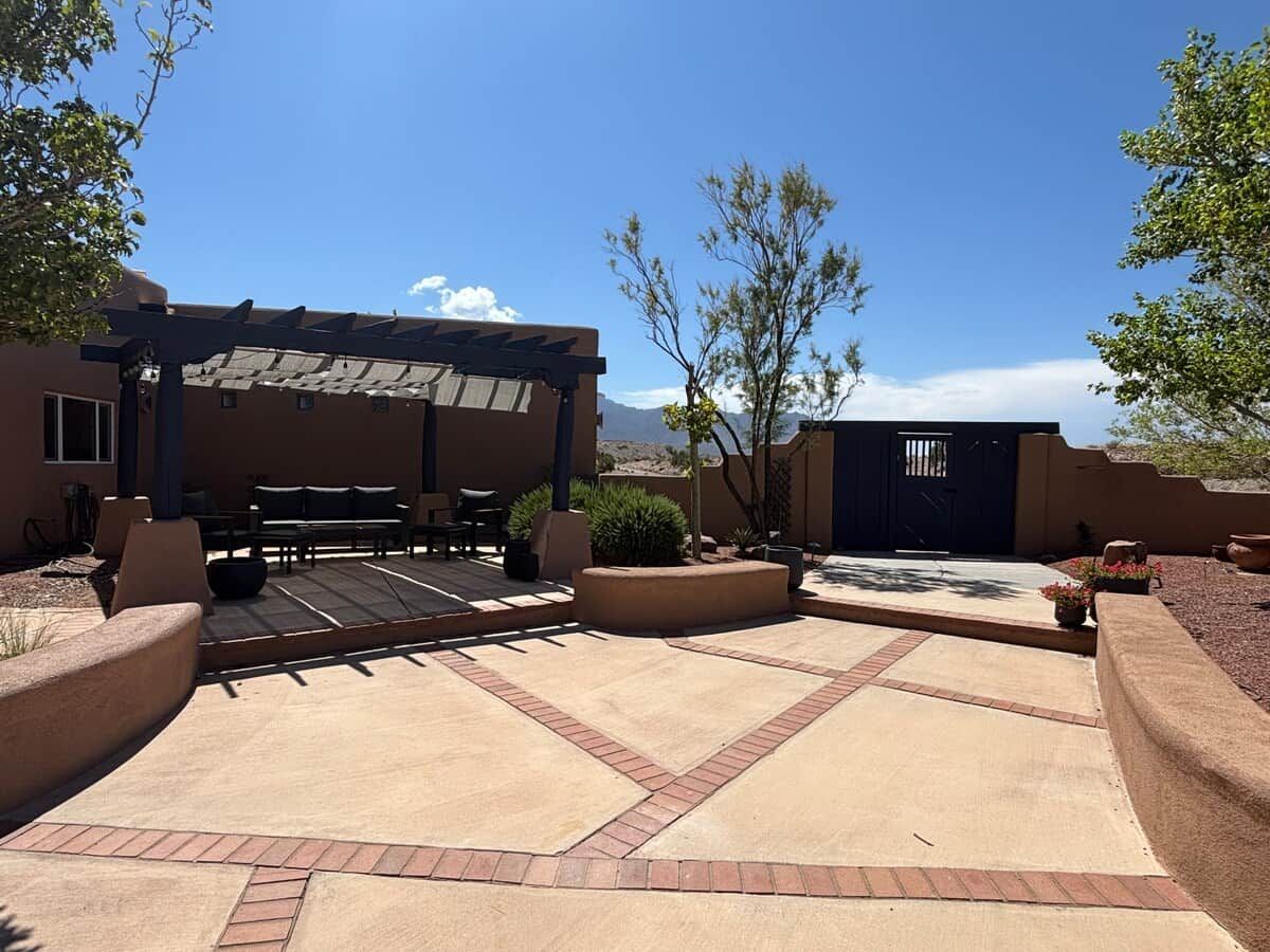 An outdoor patio area with a covered seating area, planters, and a view of the mountains.