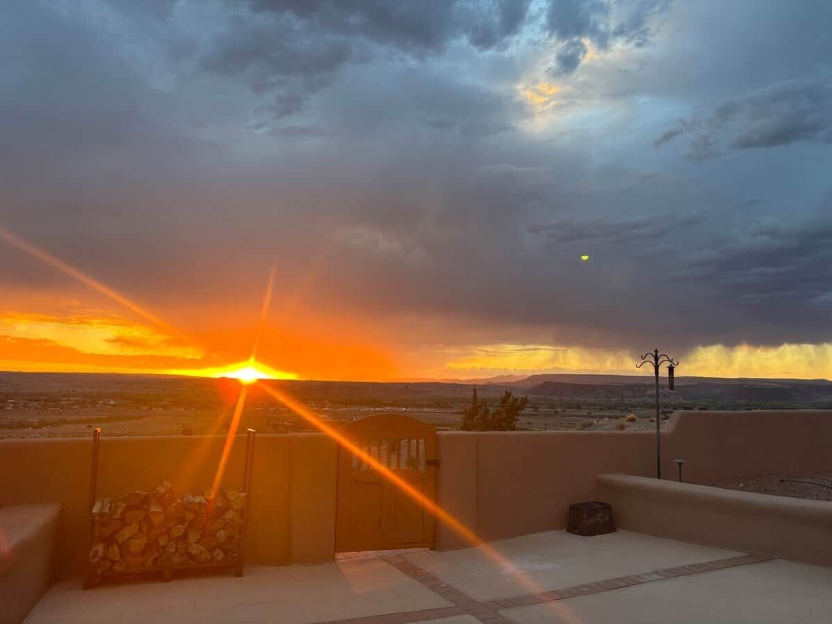 A sunset view from a balcony with a clear sky, a wooden door, and a small table.