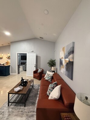 Uma sala de estar moderna com um sofá, mesa de centro e um quadro na parede.