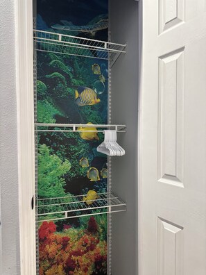 Une pièce avec une porte, un mur blanc et une étagère comprenant une unité de rangement et un porte-serviettes.