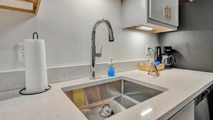 Une cuisine moderne équipée d’un évier en acier inoxydable, d’un robinet et d’une machine à café.