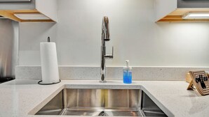 Un évier de cuisine doté d’un robinet moderne, d’un porte-essuie-tout et d’un distributeur de savon.
