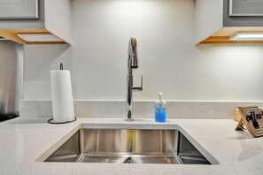 A kitchen sink with a modern faucet, a paper towel holder, and a soap dispenser. - Executive Studio - Nearby Parking - Downtown - 3F (Louisville)
