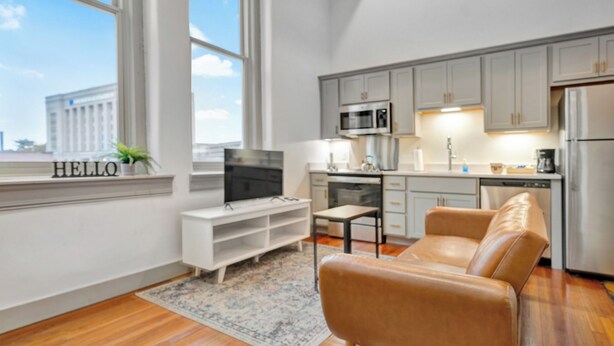 Un appartement moderne comprenant un salon, une cuisine et une grande fenêtre.