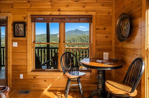 A wooden cabin with a balcony, a dining table, two chairs, and a view of mountains. - Sleeps 8, Mountain View Hot Tub, Arcade, Pool Table, 2 Mi to Gatlinburg Parkway (Gatlinburg)