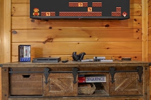 A wooden cabinet with a video game console, controllers, and a basket. - Sleeps 8, Mountain View Hot Tub, Arcade, Pool Table, 2 Mi to Gatlinburg Parkway (Gatlinburg)