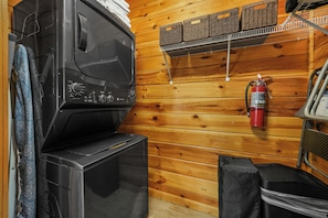 A laundry area with a washing machine and dryer, a fire extinguisher mounted on the wall, and storage baskets on a rack. - Sleeps 8, Mountain View Hot Tub, Arcade, Pool Table, 2 Mi to Gatlinburg Parkway (Gatlinburg)