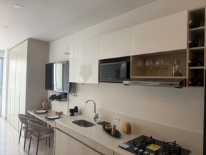 A modern kitchen with a built-in microwave, a stainless steel range hood, and a wine rack. - Apartment near the ocean at Bello Horizonte 1416 (Santa Marta)