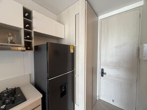 A kitchen with a black refrigerator, a stove, and a cabinet with shelves. - Apartment near the ocean at Bello Horizonte 1416 (Santa Marta)