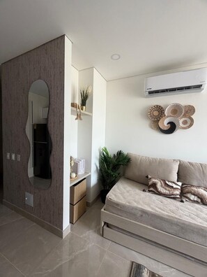Een moderne woonkamer met een bank, een grote spiegel en een luchtverwarmer aan de muur.