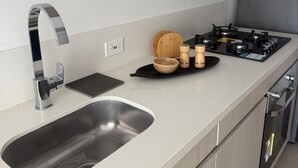 Uma cozinha moderna com uma pia de aço inoxidável, fogão a gás e tigelas de madeira no balcão.