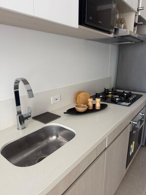 A modern kitchen with a stainless steel sink, a gas stove, and wooden bowls on the countertop. - Apartment near the ocean at Bello Horizonte 1416 (Santa Marta)