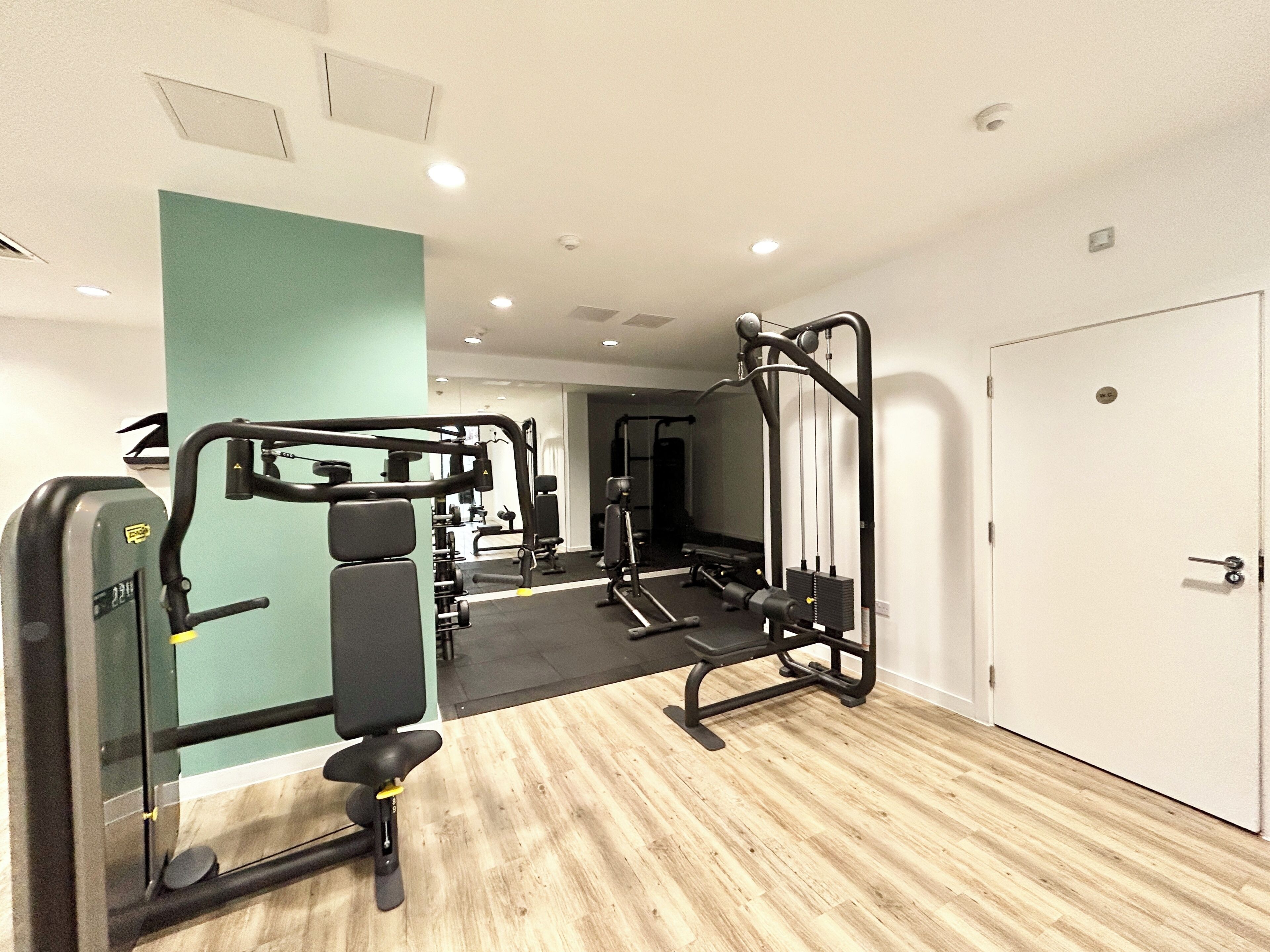 A gym with exercise equipment, a mirror, and a door.