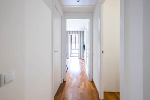 A hallway with white walls and wooden flooring leading to a bright room with a window. - Live the nomad life, fast Wi-Fi, Gaudí, sunshine, and tapas (Barcelona)