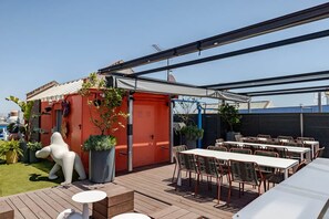 An outdoor patio with tables and chairs, a red structure, and potted plants. - Live the nomad life, fast Wi-Fi, Gaudí, sunshine, and tapas (Barcelona)