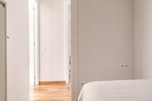 A room with a bed, a door leading to another room, and a light switch on the wall. - Live the nomad life, fast Wi-Fi, Gaudí, sunshine, and tapas (Barcelona)