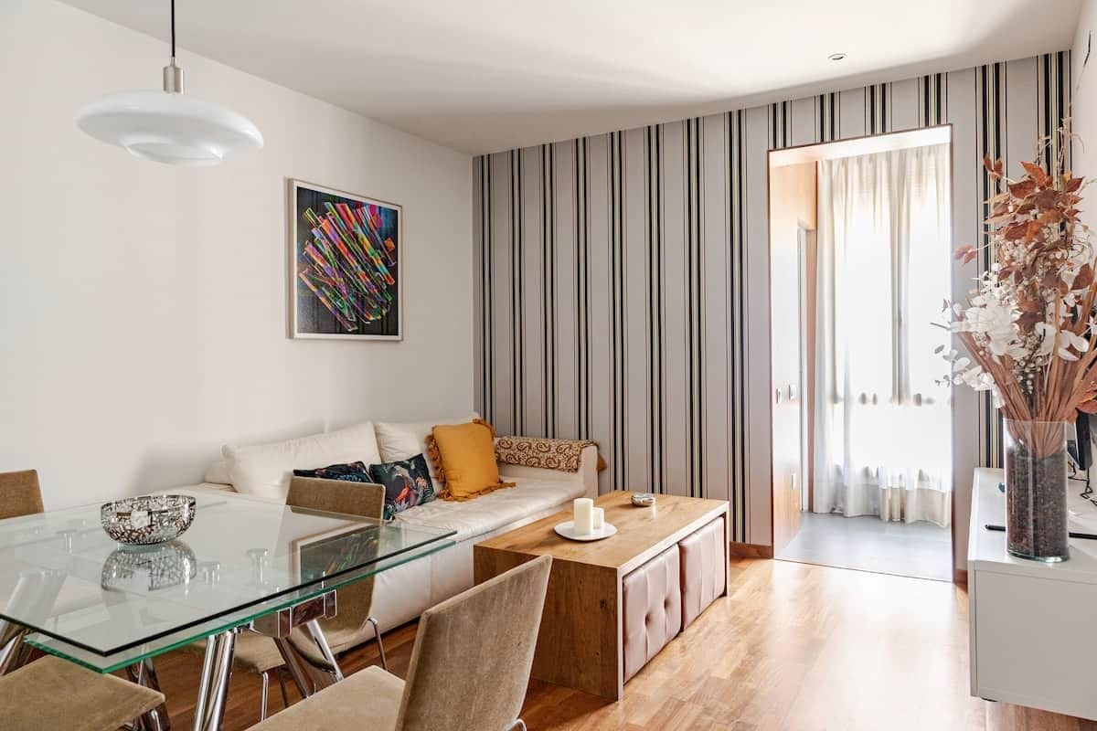 A modern living room with a glass dining table, a sofa, and a coffee table.