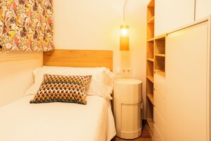 A bedroom with a bed, a bedside lamp, a waste bin, and a wall with a patterned curtain. - Fast Wi-Fi - Rooftop - 3 bedrooms - Sagrada Metro Station (Barcelona)