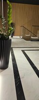 Un piso de mármol con una franja negra, una planta en maceta y una pared de madera al fondo.