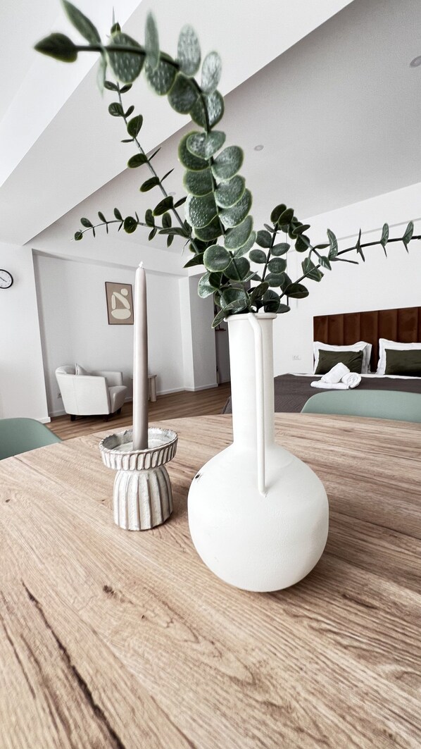 Un interior moderno con una mesa de madera, dos jarrones blancos y una planta.