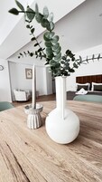 Un interior moderno con una mesa de madera, dos jarrones blancos y una planta.