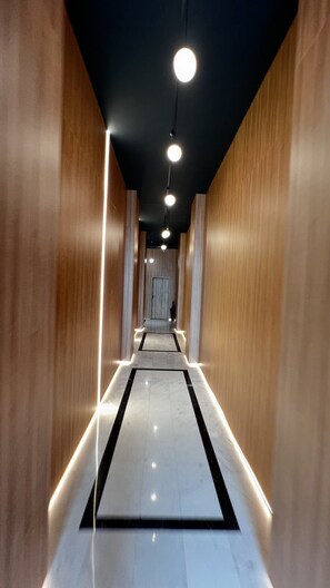 A corridor with wooden walls, a marble floor, and ceiling lights. - AeroGrey Residence Apartments (Tunari)