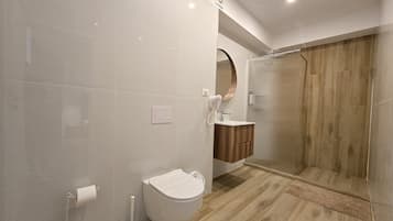 A modern bathroom with a toilet, bidet, and a shower area.