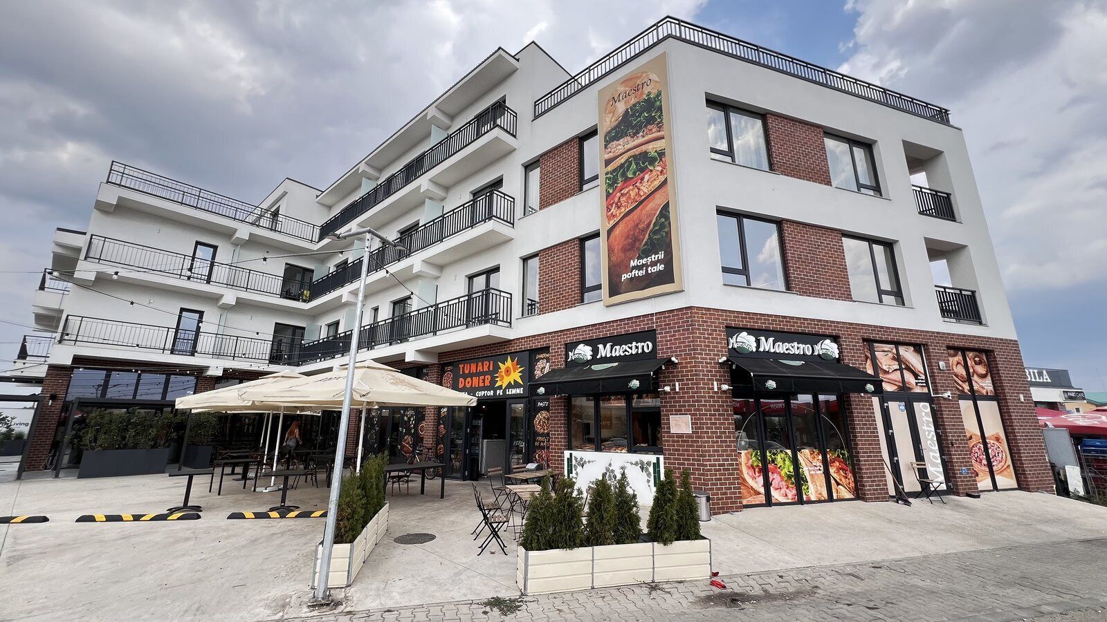 Um edifício com vários andares, com um restaurante chamado 'Maestro' no andar térreo.