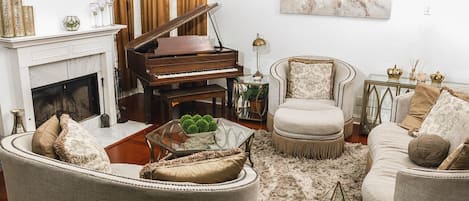 A living room with a grand piano, a fireplace, a sofa, and a coffee table.