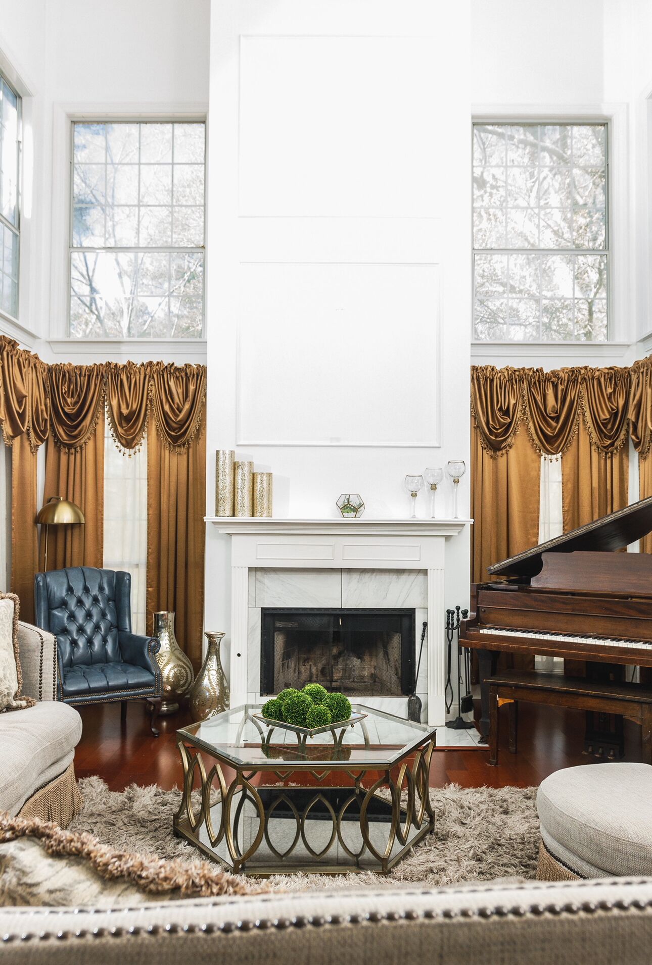 A spacious living room with a grand piano, a fireplace, and a large window with curtains.