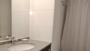 Baño con lavamanos de granito, espejo, cortina de ducha y retrete.