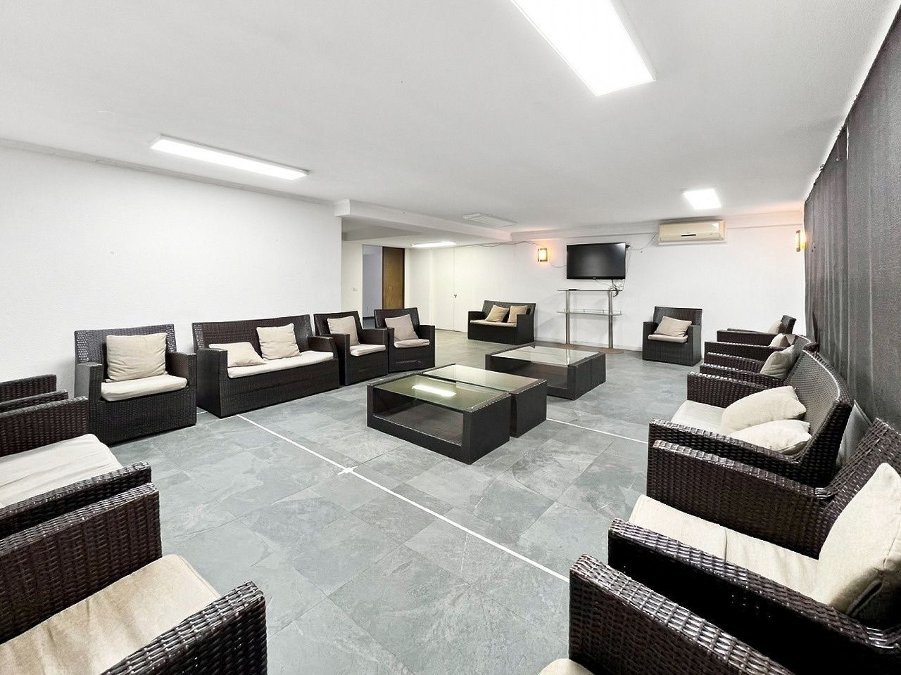 A modern lounge area with wicker furniture and a central glass coffee table.