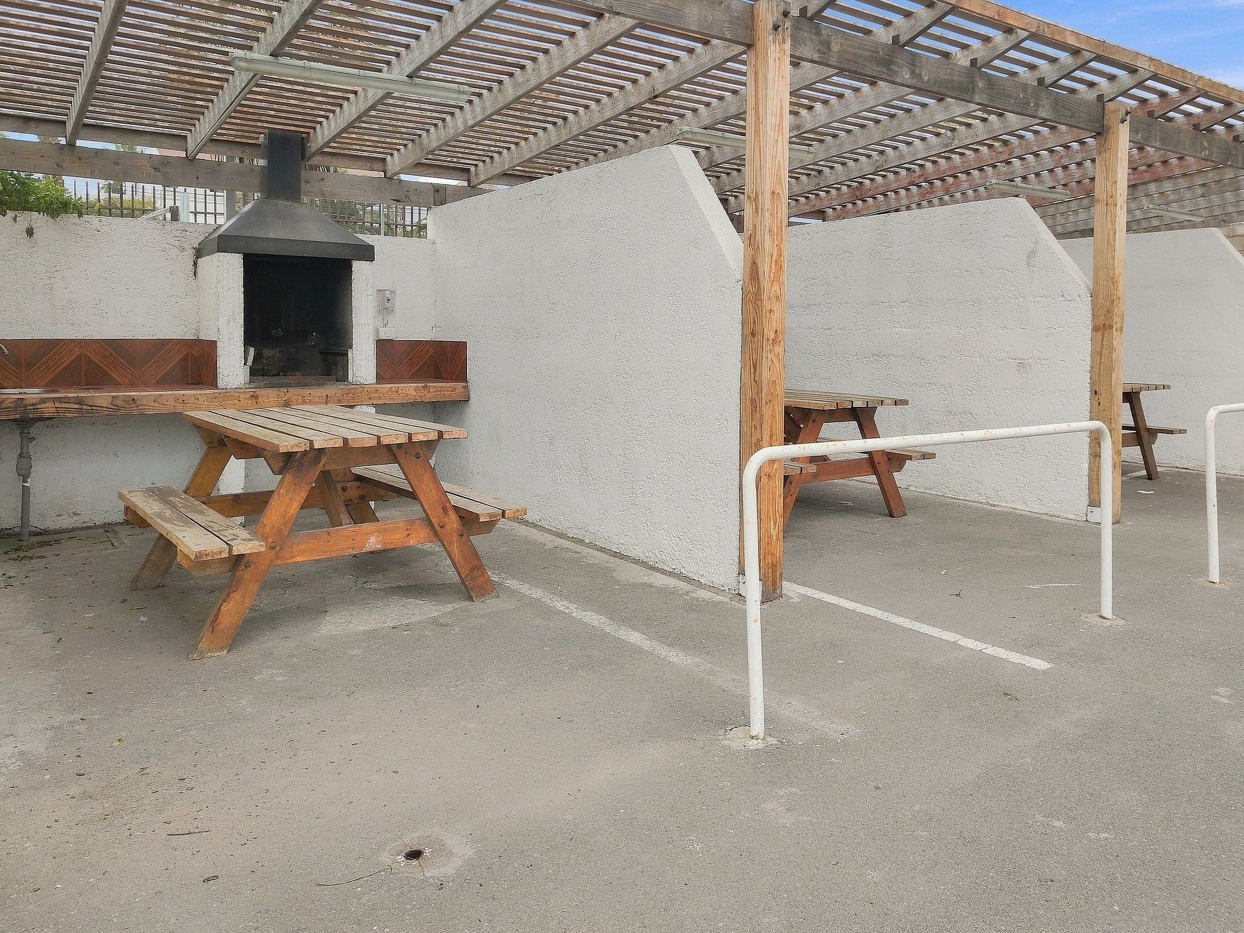 Un'area esterna coperta con tavoli da picnic e una griglia per barbecue.